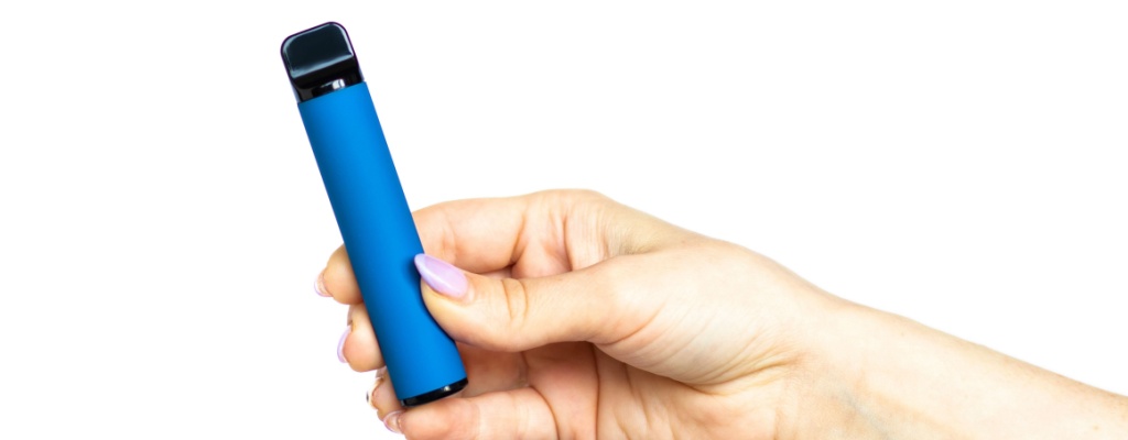 A hand holds a disposable vape in front of a white background.